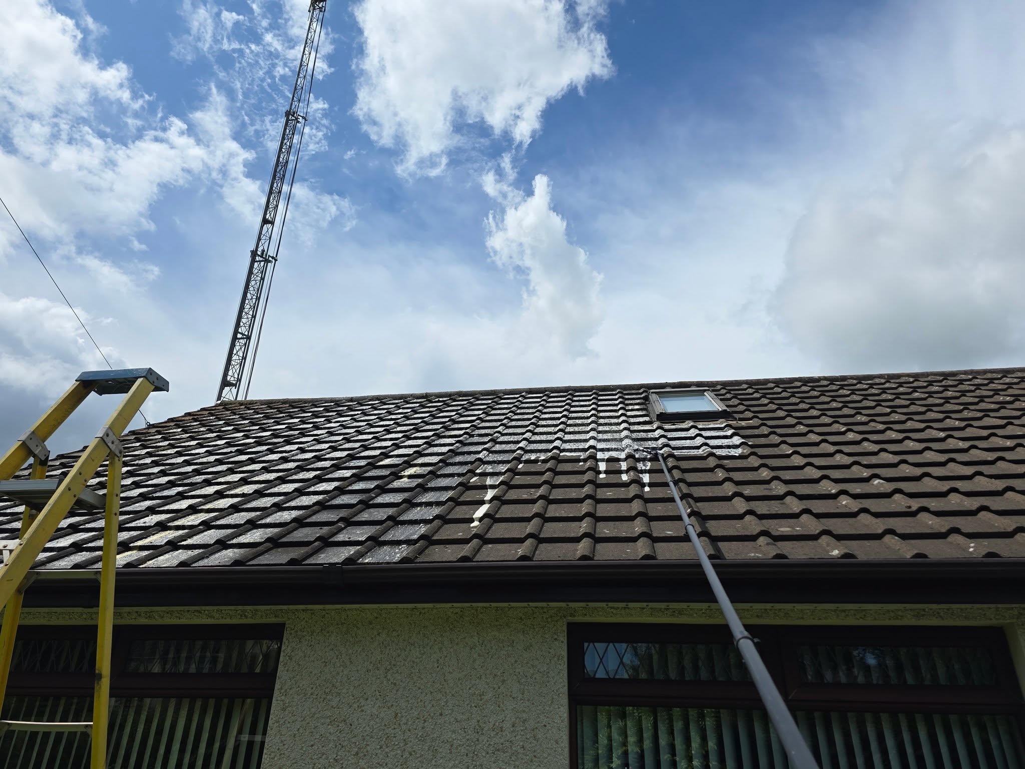 Roof cleaning treatment being applied to residential property with scaffold tower